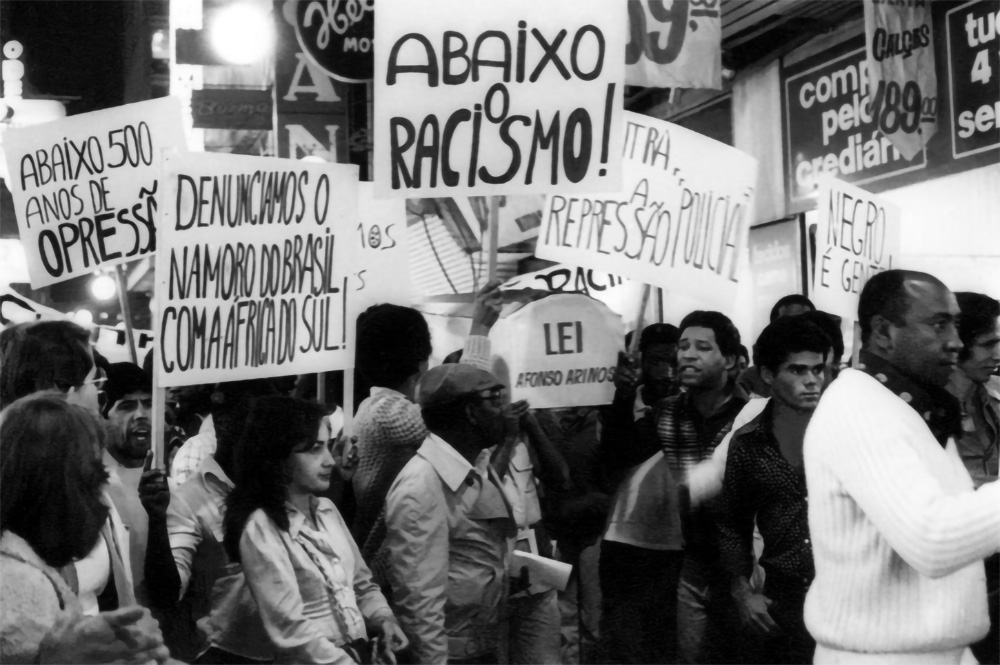 Cartazes e manifestantes contra o racismo (Foto: Reprodução - Politize!)