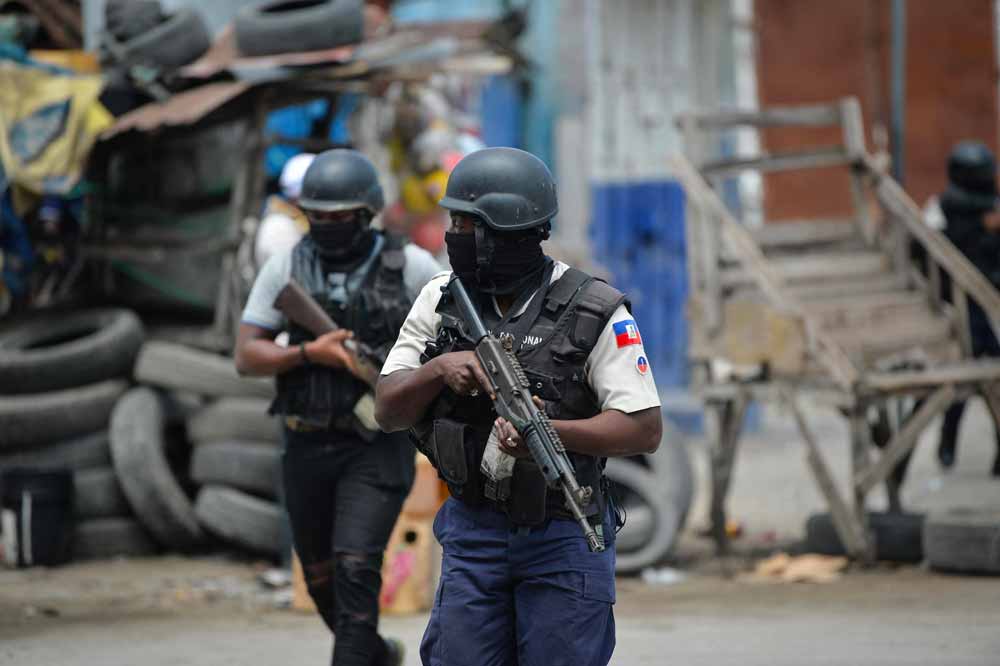 Agentes de polícia haitianos patrulham um bairro em meio à violência estrutural infligida à grande maioria da população, no centro de Porto Príncipe, em 25 de abril de 2023. (Foto: Richard Pierrin/AFP)