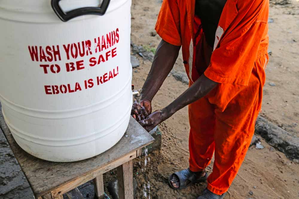 Prisão Central de Monrovia, Libéria. Água com cloro para lavar as mãos com aviso, dentro da prisão. (Imagem: T. Glass)