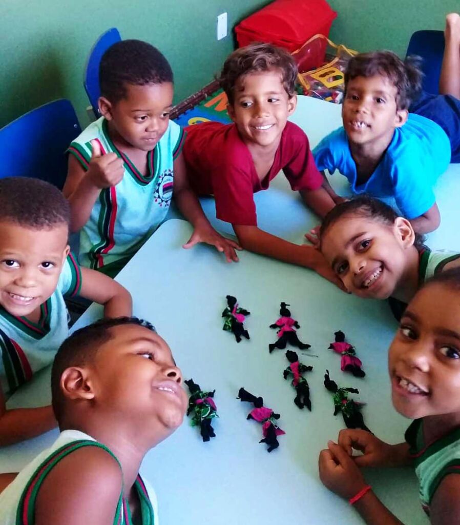 Foto colorida mosta alunas do Colegio Maria Gregoria fazendo atividade escolar criando bonecas pretas de pano