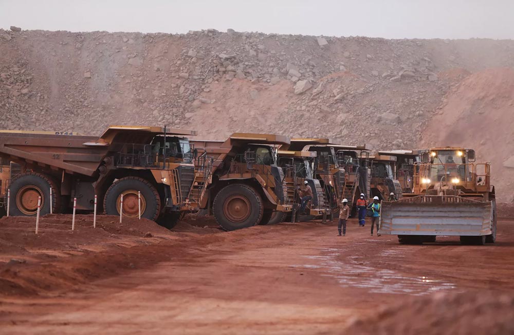 Caminhões de mineração e máquinas pesadas operam em área de extração mineral em Burkina Faso.