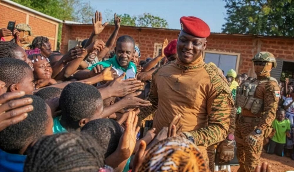 Ibrahim Traoré cumprimenta apoiadores durante visita pública em Burkina Faso, cercado por civis e militares.